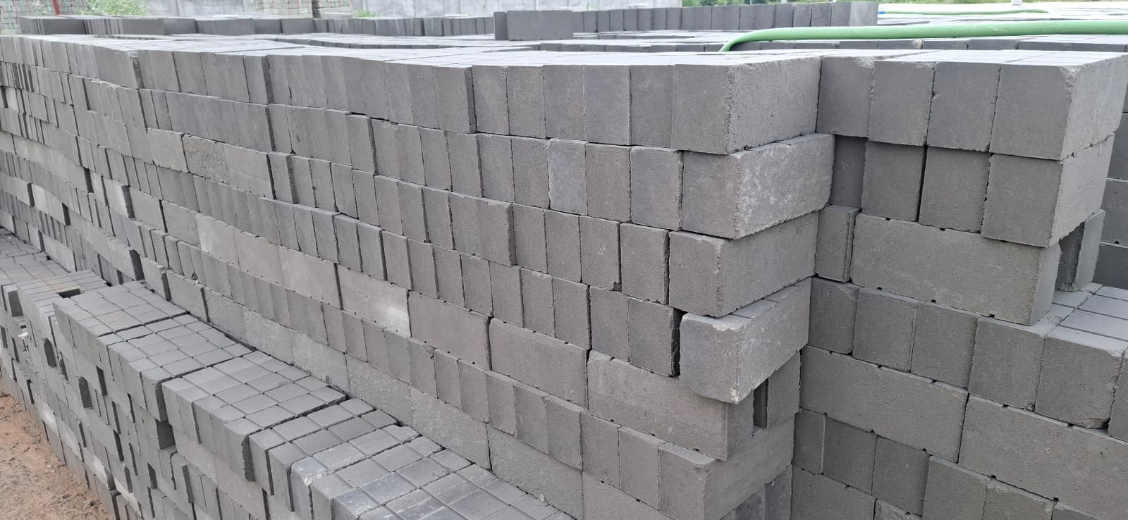 Close-up of neatly stacked grey TVM flyash bricks showing uniform edges and smooth finish